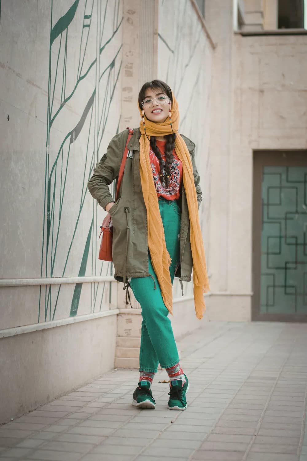 زنی با کاپشن کتان و شال نارنجی در حال راه رفتن